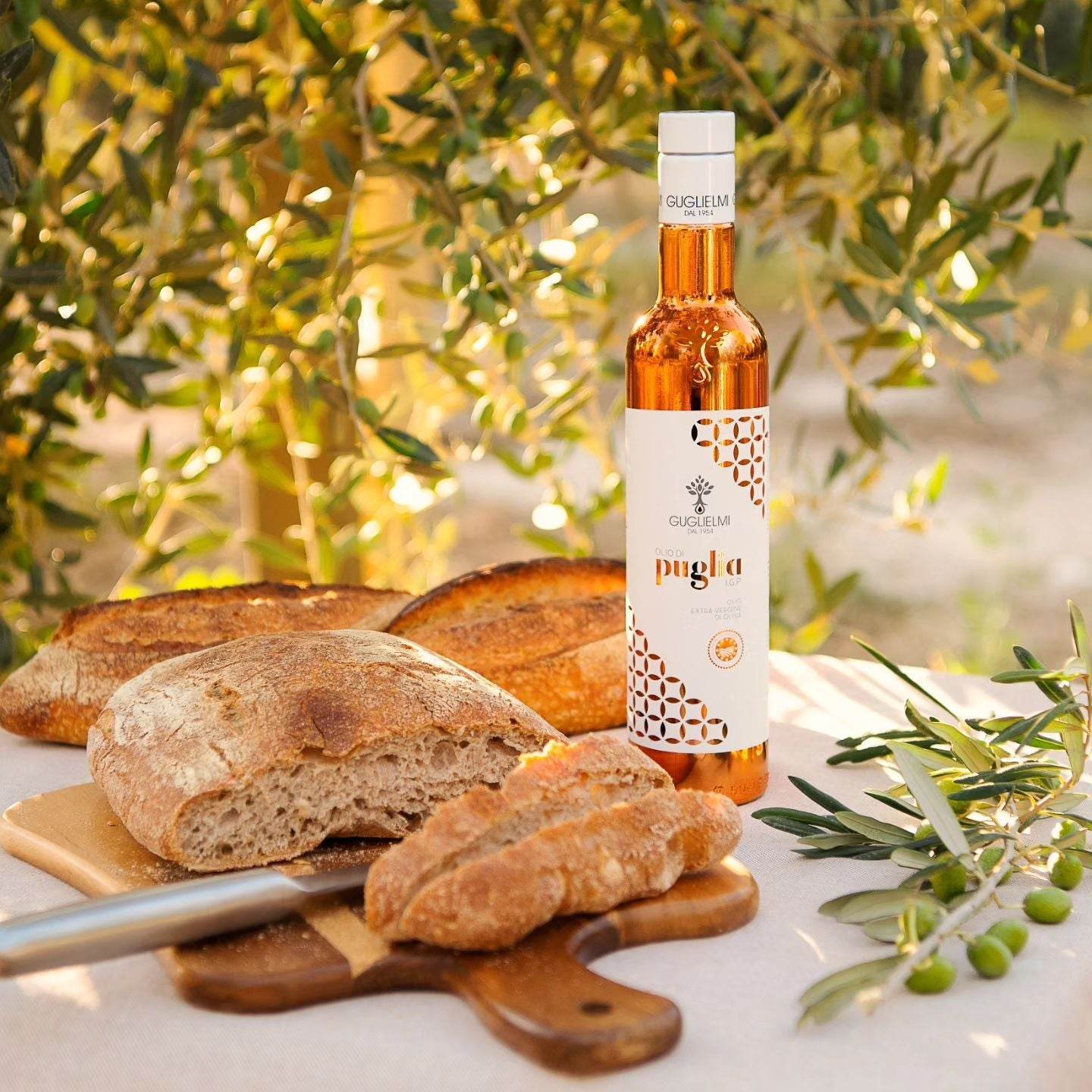 Best of Italiaanse Extra Vierge Olijfolie bottle with artisanal bread on wooden board, surrounded by olive branches