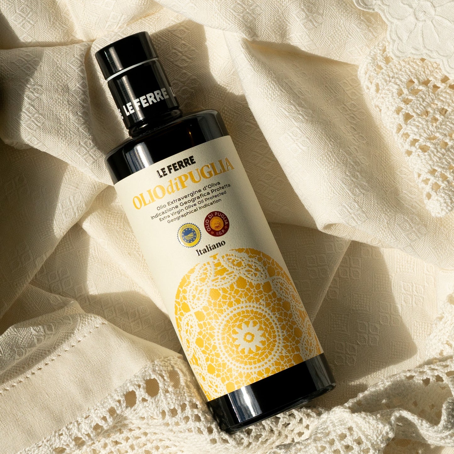 LeFerre Olio di Puglia IGP premium olive oil bottle with ornate yellow mandala design on cream textured background