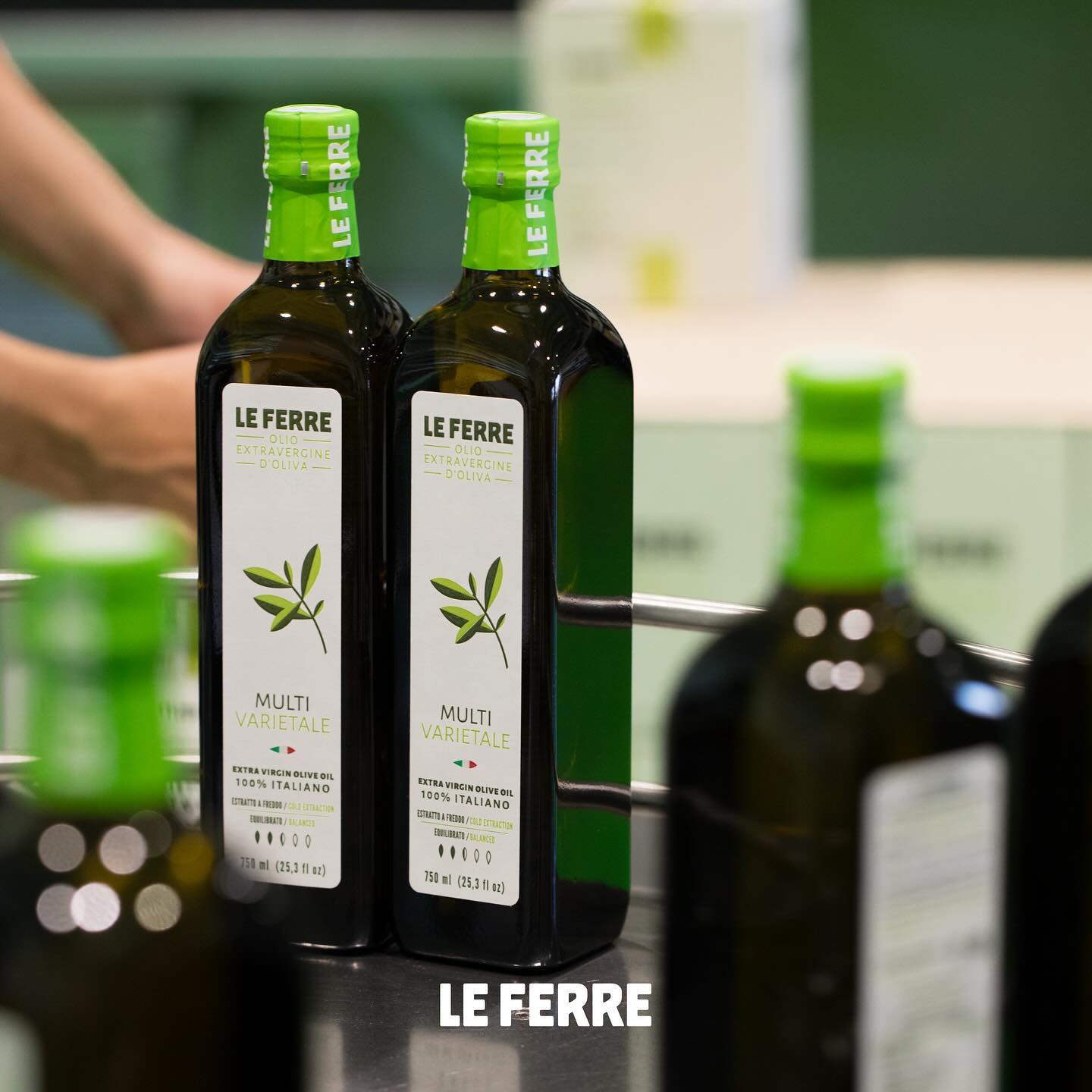 LeFerre Multivarietale olive oil bottles with green caps and olive branch labels displayed on dark surface