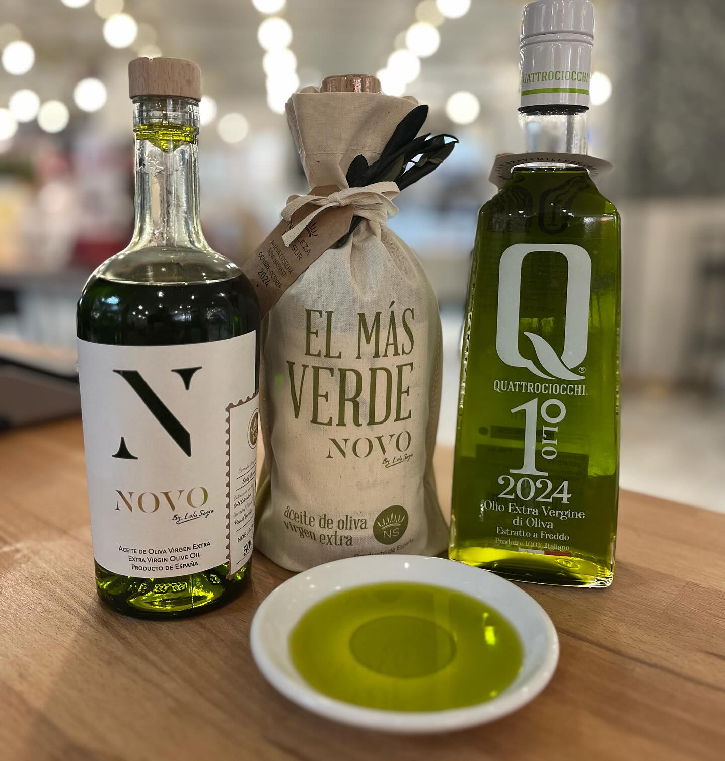 Nobleza del Sur NOVO premium olive oil bottles displayed with tasting plate showing bright green early harvest oil