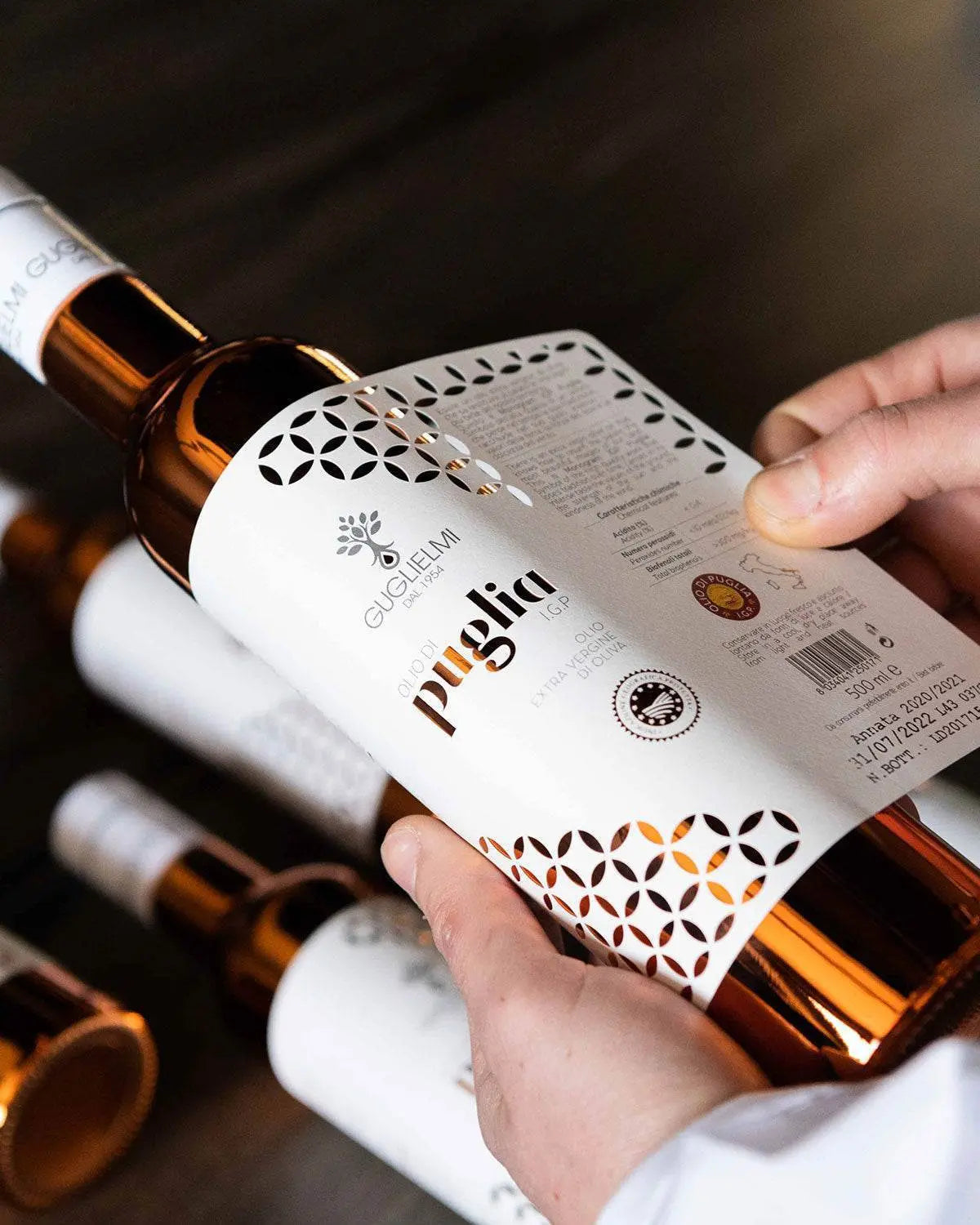 Beste Olijfolie Set 2025: Premium Italian olive oil bottle with geometric pattern label being held against dark background