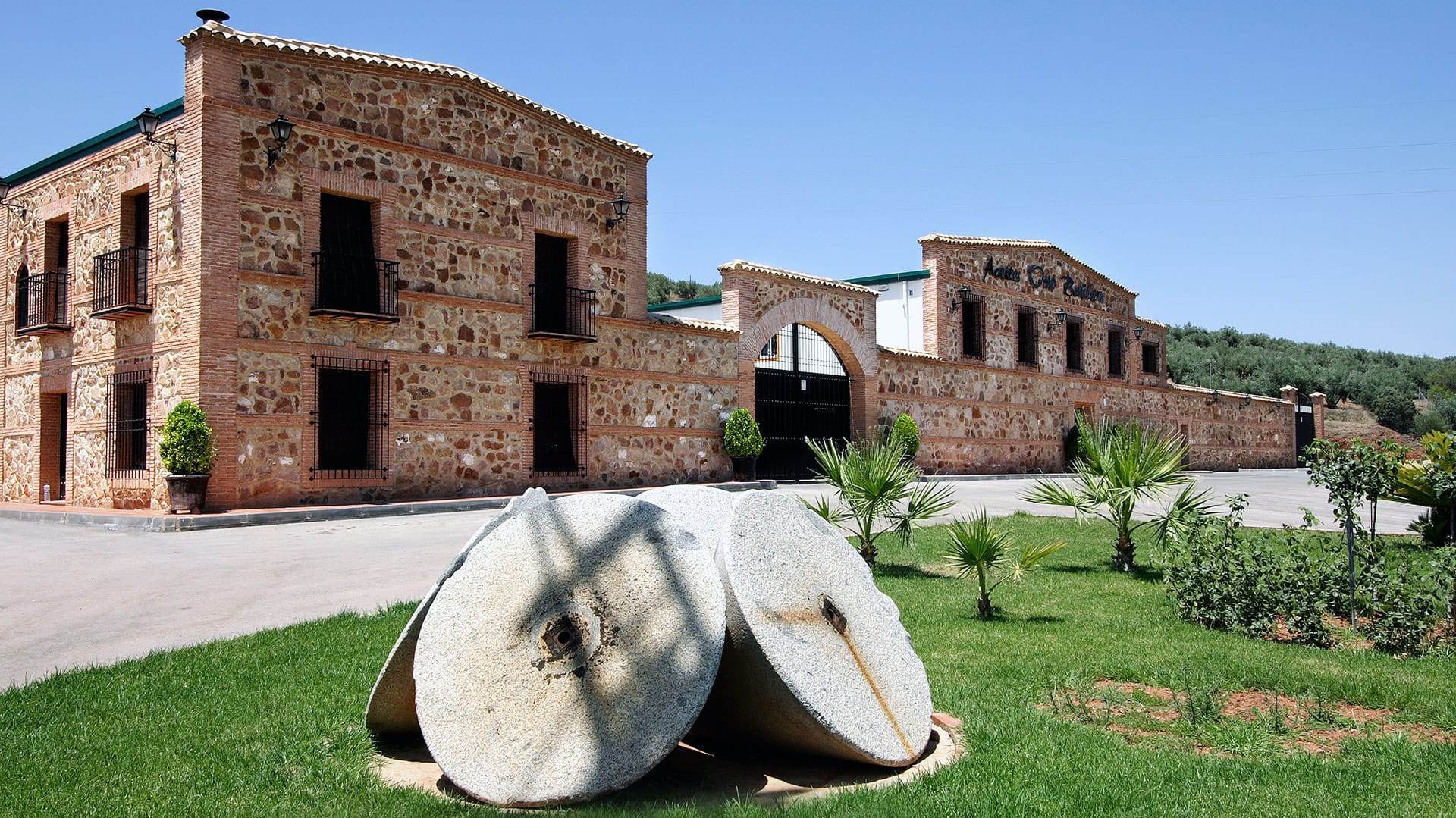 Casa del Agua 5LT - Traditional stone olive mill building with millstones on grass and rustic architecture in Spanish countryside