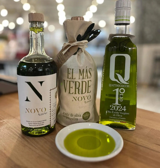 Helder groene olijfolie van de nieuwe oogst in een proefschaaltje naast twee flessen NOVO