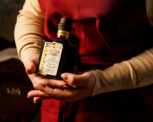 Vrouw overhandigt een cadeauverpakte fles balsamico als verrassingscadeau