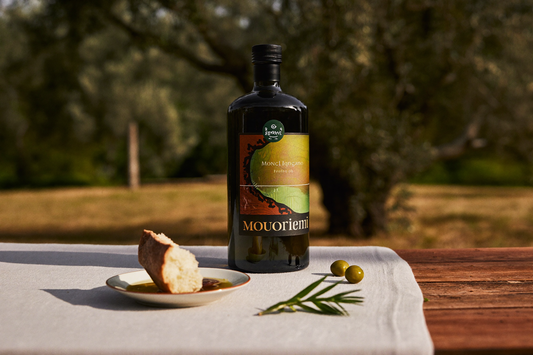 Olijfolie voor gewichtsverlies — Guglielmi Monogram Fruttato fles op witte linnen tafel in Mediterrane tuin